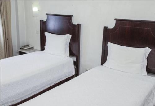 a bedroom with two beds with white sheets and wooden headboards at Hotel Palanca in Porto