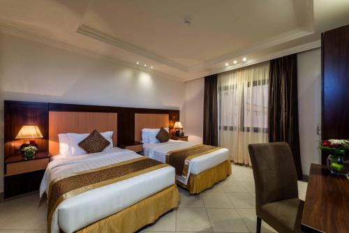 Habitación de hotel con 2 camas y escritorio en Boudl Al Rass, en Al Rass