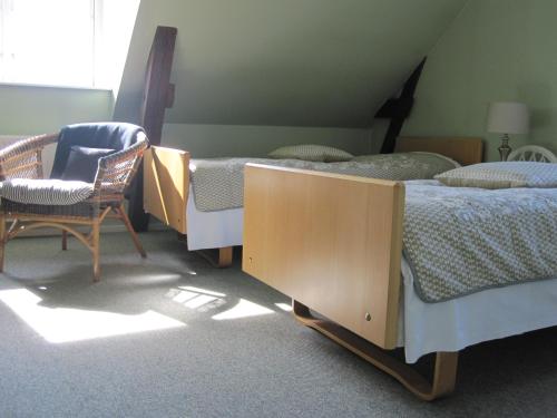 a bedroom with two twin beds and a chair at Hotel Postgaarden in Skælskør