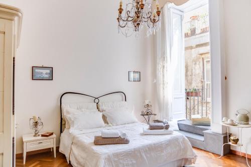 a white bedroom with a bed and a chandelier at B&B Nilo in Naples
