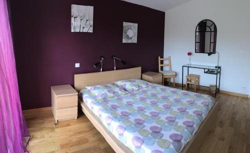 a bedroom with a large bed with a purple wall at Les Condamines in Antoingt