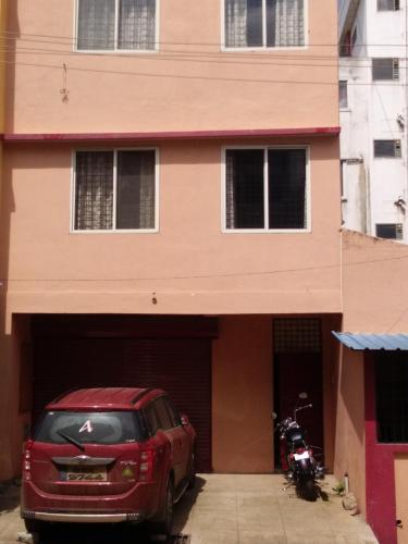 un'auto rossa parcheggiata di fronte a un edificio di Marina Stay a Chikmagalūr