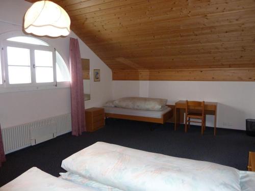 a bedroom with two beds and a table and a window at Berghaus Männlichen in Grindelwald