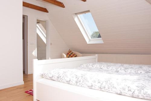 Cama blanca en habitación con 2 ventanas en Landhaus Lillesand, en Esens