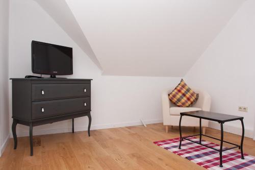 a living room with a tv on a dresser and a chair at Landhaus Lillesand in Esens