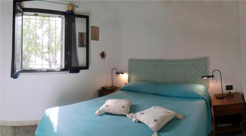 a bedroom with a blue bed with two pillows on it at Cottage Fuile 'E Mare in Orosei