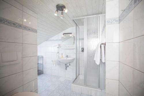 a white bathroom with a sink and a shower at Pension Winklerkreuz in Alpbach