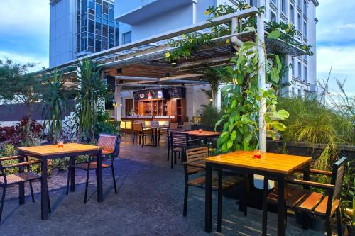 a restaurant with wooden tables and chairs in front of a building at Jambuluwuk Malioboro Hotel Yogyakarta in Yogyakarta