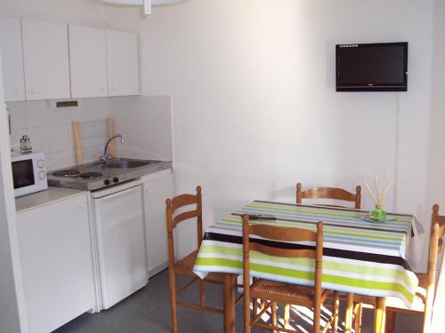 eine kleine Küche mit einem Tisch mit Stühlen und einem Waschbecken in der Unterkunft Studio Gaindeguia 45 in Cambo-les-Bains