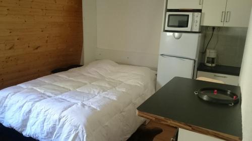 レ・デュー・アルプにあるDiamant 3 Fのベッド1台、テーブル、電子レンジが備わる小さな客室です。