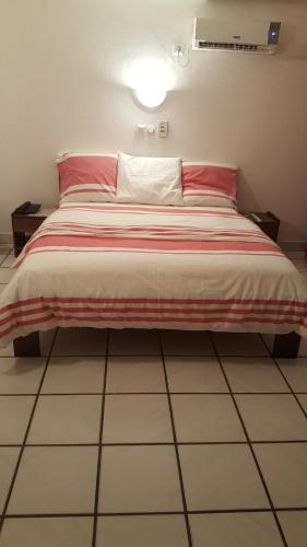 a bed with a red and white blanket on it at Résidence Saint-Jacques Brazzaville in Brazzaville