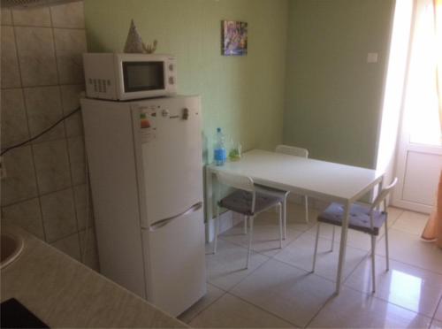 uma cozinha com uma mesa e um micro-ondas em cima de um frigorífico em Apartment on Oktyabrskaya 21 em Belomorsk