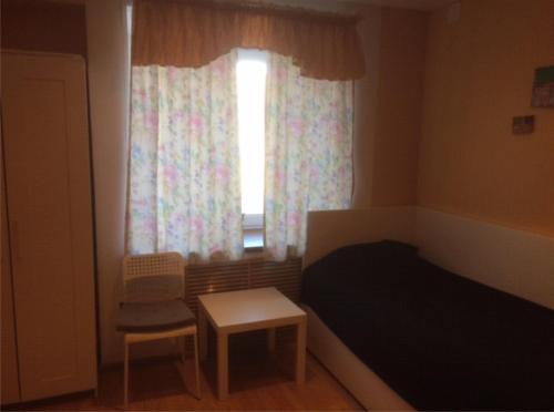 a bedroom with a bed and a window with a chair at Apartment on Oktyabrskaya 21 in Belomorsk