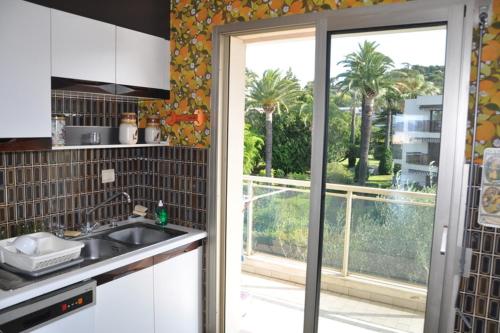 une cuisine avec un évier et un balcon avec des palmiers dans l'établissement Karolina Properties - Ascot Appartement, à Cannes
