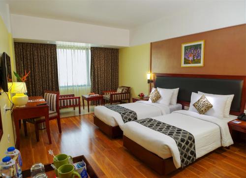 a hotel room with two beds and a living room at Classic Sarovar Portico Trivandrum in Trivandrum