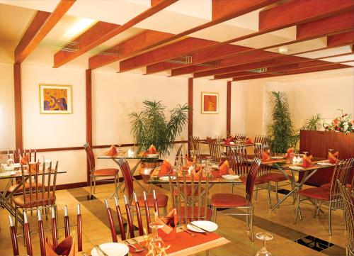 a restaurant with tables and chairs in a room at Classic Sarovar Portico Trivandrum in Trivandrum