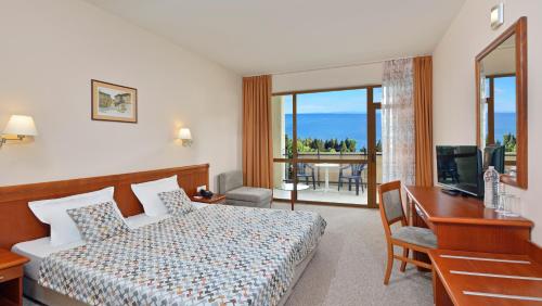 a hotel room with a bed and a desk and a television at Sol Nessebar Bay All Inclusive in Nesebar