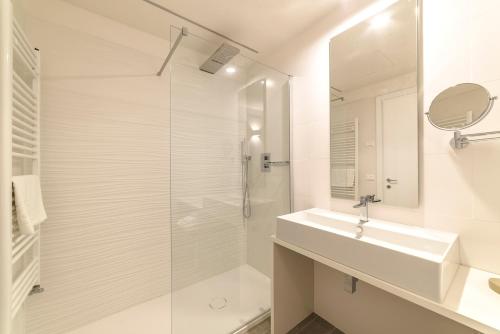 a white bathroom with a sink and a shower at Hotel Tenda Rossa in Marina di Carrara