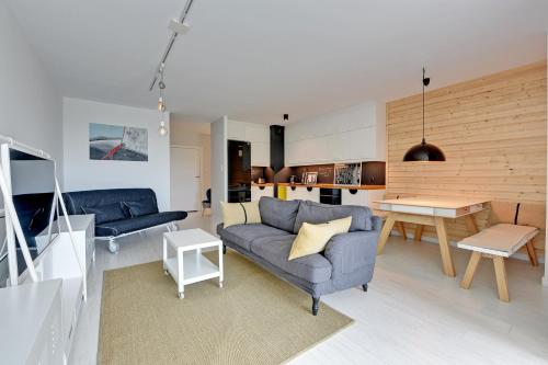ein Wohnzimmer mit einem blauen Sofa und einem Tisch in der Unterkunft NORDBYHUS Apartamenty Chmielna Park in Danzig
