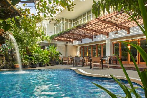 una piscina en un patio con una fuente en Jambuluwuk Malioboro Hotel Yogyakarta, en Yogyakarta