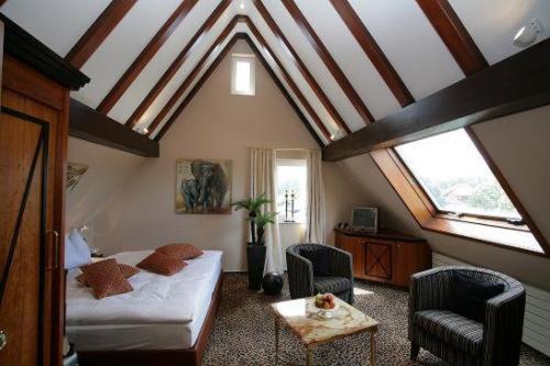 ein Schlafzimmer mit einem Bett und zwei Stühlen im Dachgeschoss in der Unterkunft Hotel-Restaurant Arneggers Adler in Tiefenbronn