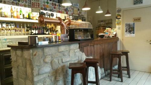 a bar with two stools and a counter with alcohol at Locanda La Tana Del Luppolo in Valmadrera