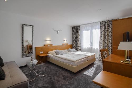 a bedroom with a bed and a couch and a mirror at Hotel Maxim in Langenfeld