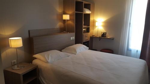 a bedroom with a large white bed with two pillows at Best Western Linko Aubagne in Aubagne