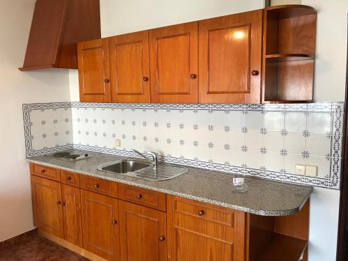 uma cozinha com um lavatório e armários de madeira em Residêncial Colaço em Alcoentre