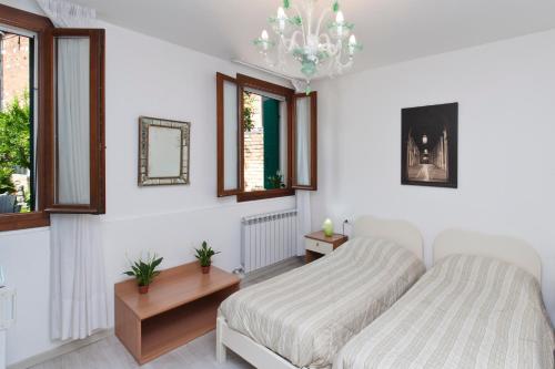 a bedroom with a bed and a chandelier and windows at Ca' Del Pomo Grana' in Murano