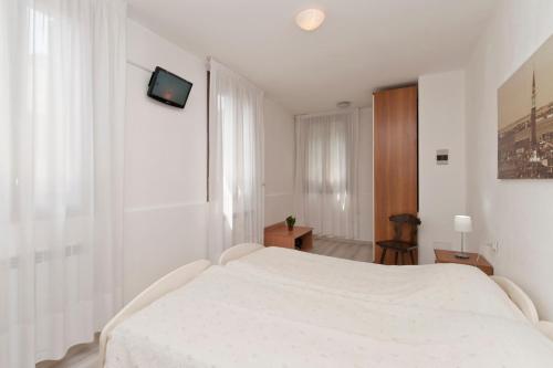 a white bedroom with a white bed and a window at Ca' Del Pomo Grana' in Murano