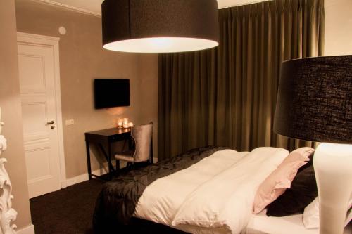 a hotel room with a bed and a lamp at Hotel Huis van Bewaring - Bijzonder boutique hotel in historisch pand in Almelo