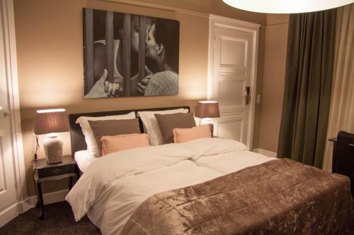 a bedroom with a large bed and a painting on the wall at Hotel Huis van Bewaring - Bijzonder boutique hotel in historisch pand in Almelo