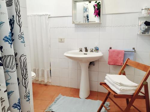 ein Badezimmer mit einem Waschbecken, einem Spiegel und einem Stuhl in der Unterkunft Studio Alli in Pantelleria