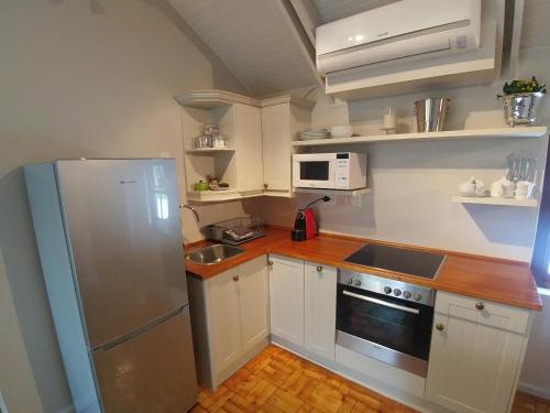 a small kitchen with white cabinets and a refrigerator at Aan De Vliet Guest House in Stellenbosch