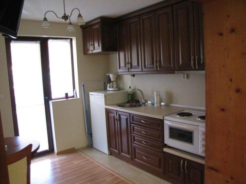 a kitchen with wooden cabinets and a white refrigerator at Guest House Vergie in Sapareva Banya