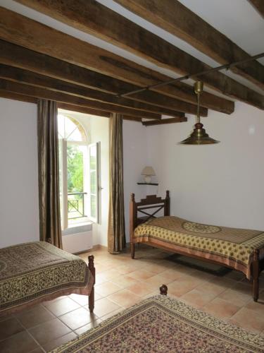 1 dormitorio con 2 camas y ventana grande en Chambres d'hôtes du Moulin de la Chaussee, en Saint-Denis-dʼOrques