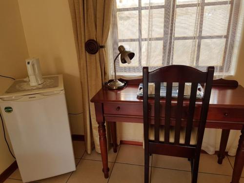 a desk with a lamp and a chair next to a window at Marlot Guest House in Polokwane
