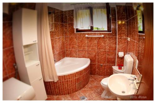 a bathroom with a tub and a toilet and a sink at Villa Marin in Pag