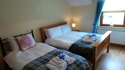 a bedroom with two beds with towels on them at Saint Patrick's Cottages (Downpatrick) in Downpatrick