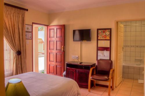 a bedroom with a bed and a desk and a chair at Marlot Guest House in Polokwane