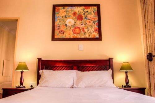 a bedroom with a bed with a painting on the wall at Marlot Guest House in Polokwane