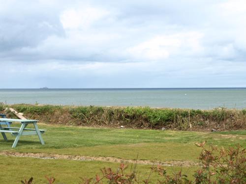 a picnic table sitting on the grass near the ocean at Argyle Lodge in Rush