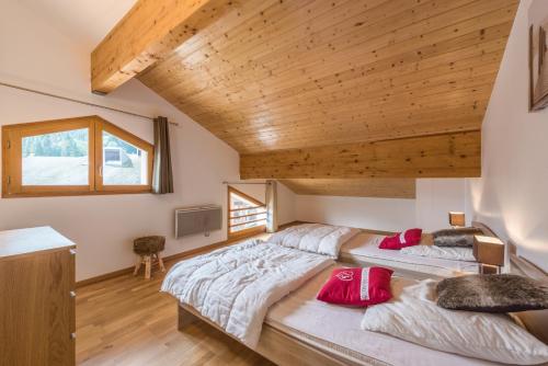 two beds in a bedroom with a wooden ceiling at L'Eden Ski aux Pieds in Morillon