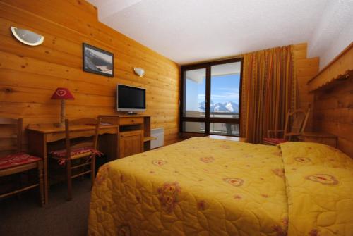 une chambre avec un lit, un bureau et une télévision dans l'établissement Hôtel Le Dôme, à L'Alpe-d'Huez