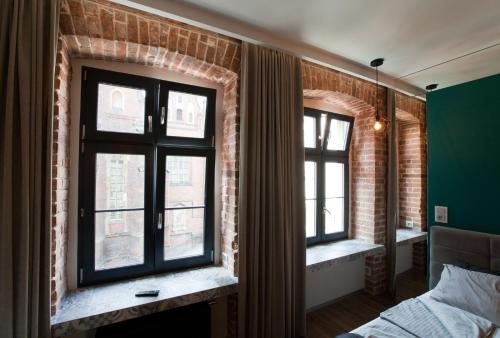 a bedroom with two windows and a brick wall at 2/3 APARTMENTS Old Town in Wrocław
