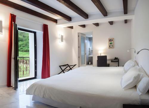 a bedroom with a large white bed and a window at Finca Portizuelo in Luarca