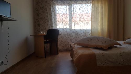 a bedroom with a bed and a desk and a window at Casa Rustica Apart & Rooms in Cîmpineanca