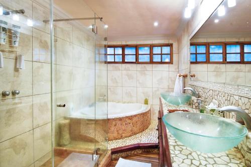 a bathroom with a tub and a glass shower at Villa Dona Ines in Tamarindo