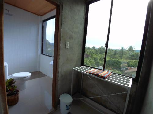 a bathroom with a toilet and a large window at Eddie's Homestay in Lhonga